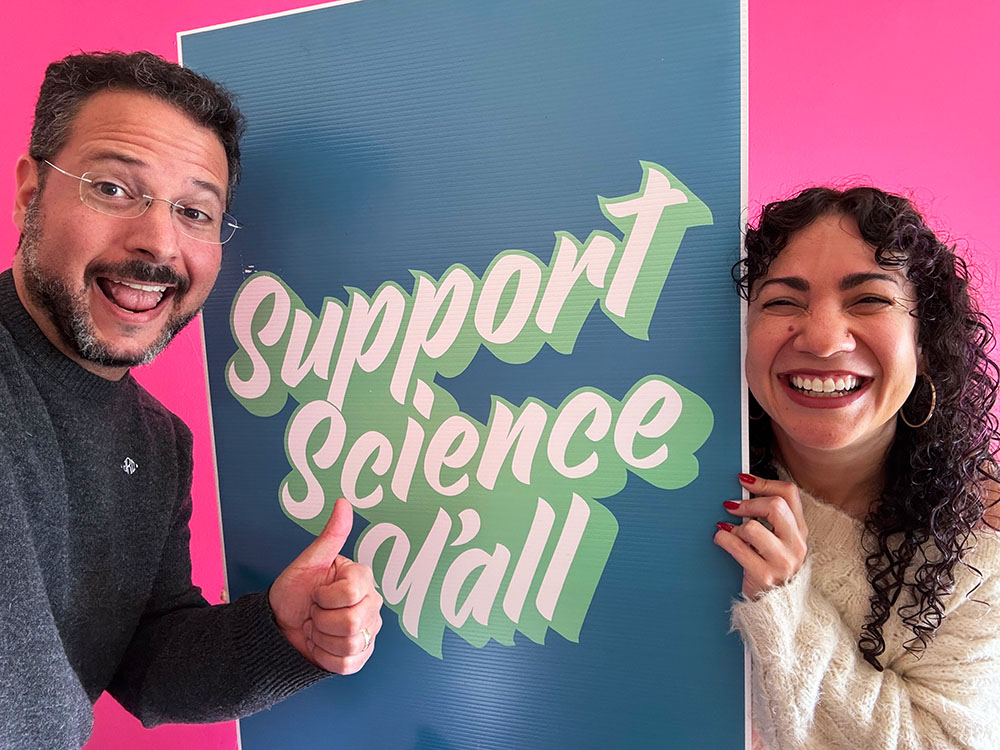 Jordan and Meisa holding a Support Science Y’all sign.